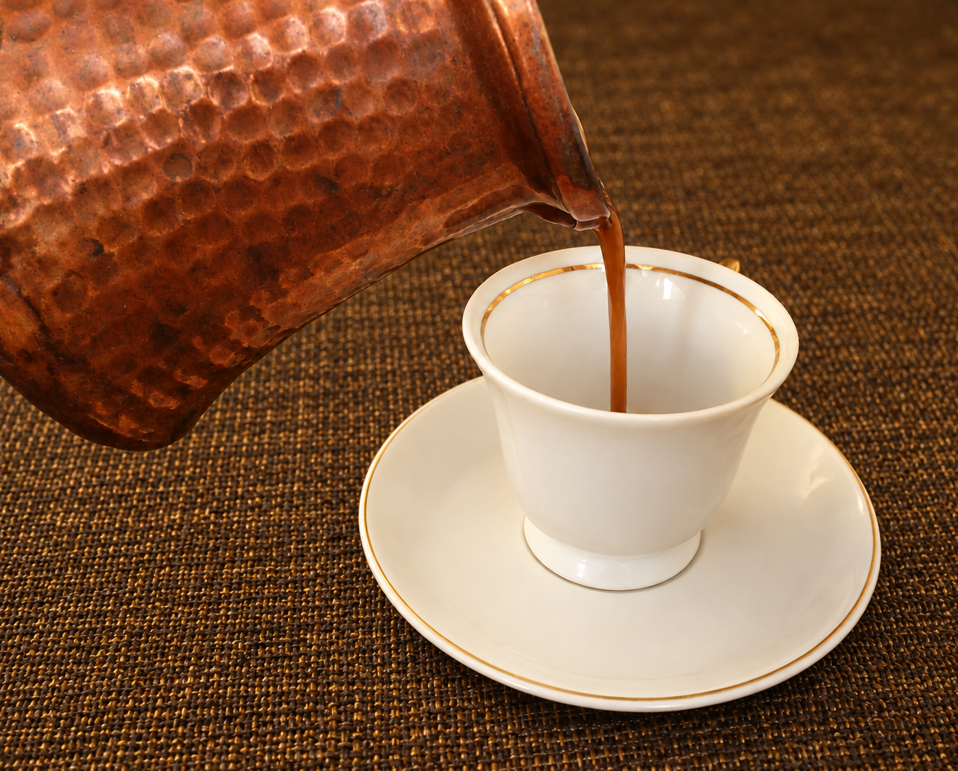 Türkischer Kaffee wird in eine weisse Tasse mit Goldrand gegossen
